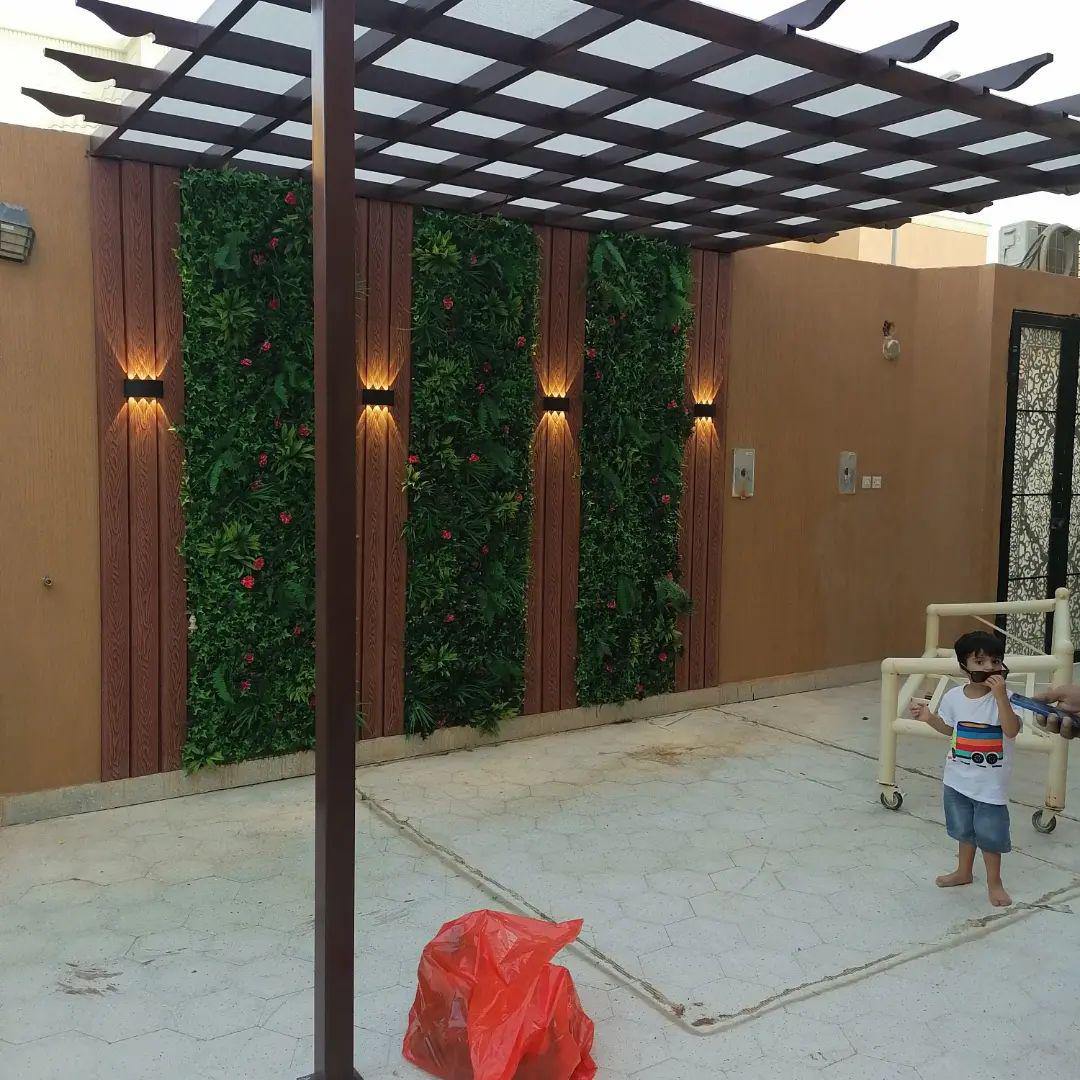 جدار خارجي ببديل الخشب ونباتات ديكورية وإضاءة